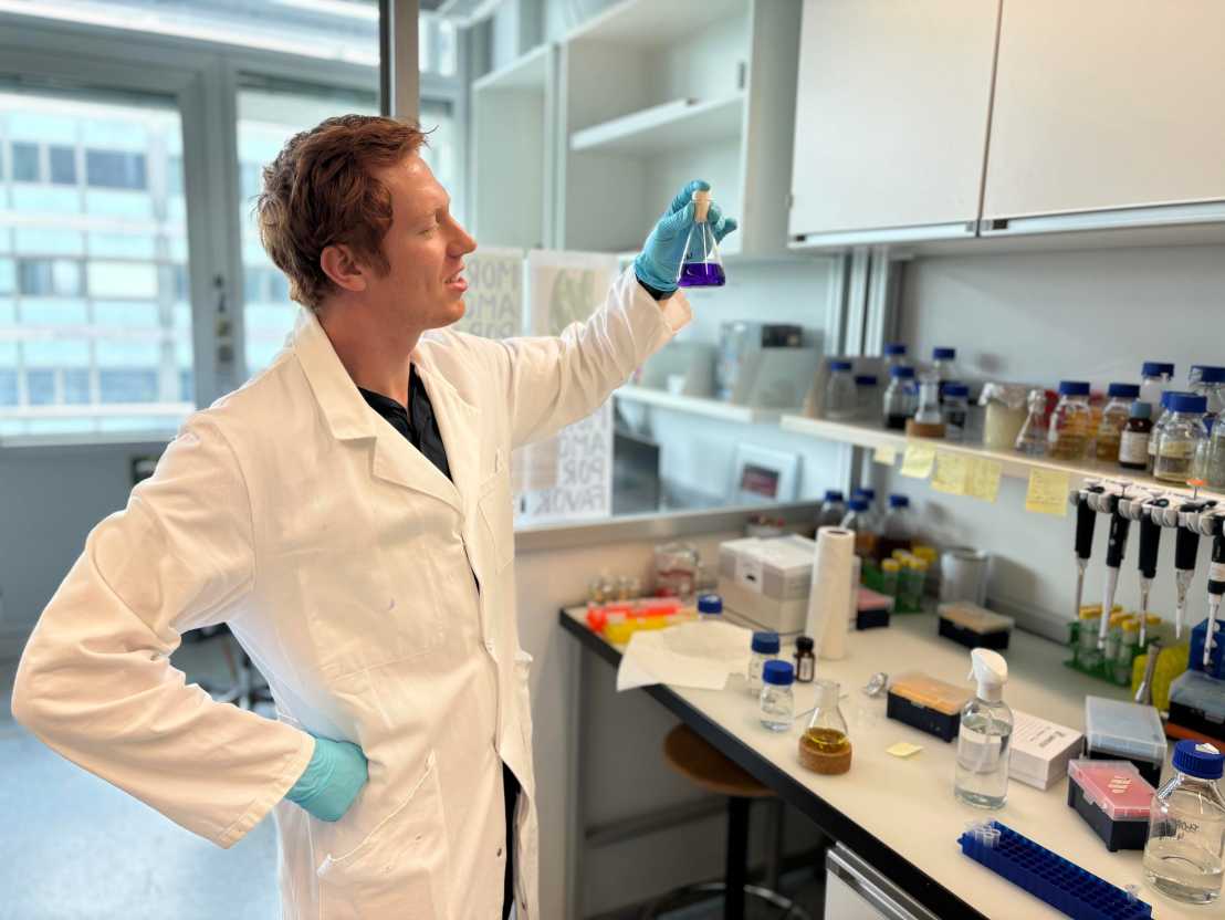 Picture of lab member looking at a flask